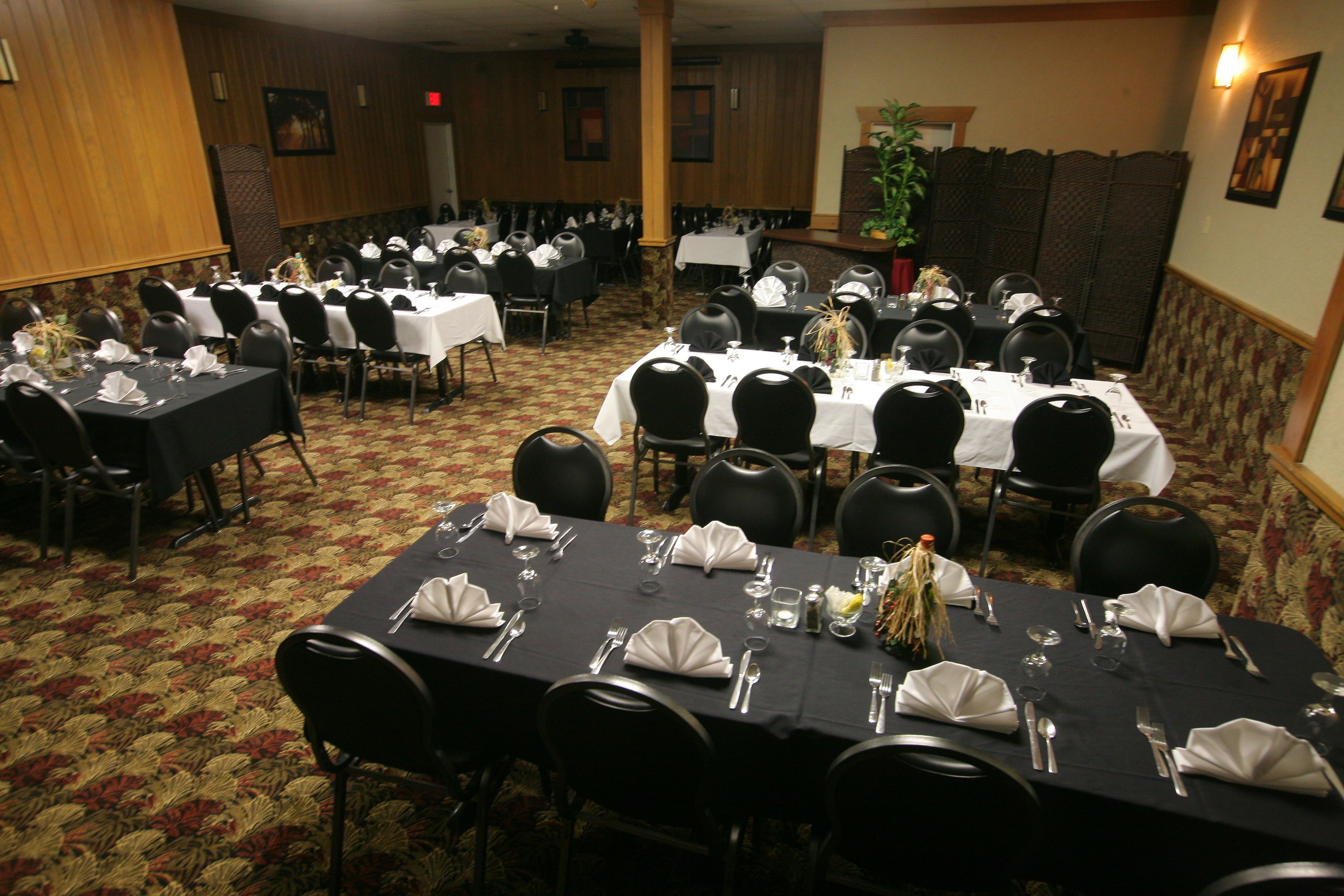 A banquet hall with multiple tables set for dining, arranged in rows with chairs.