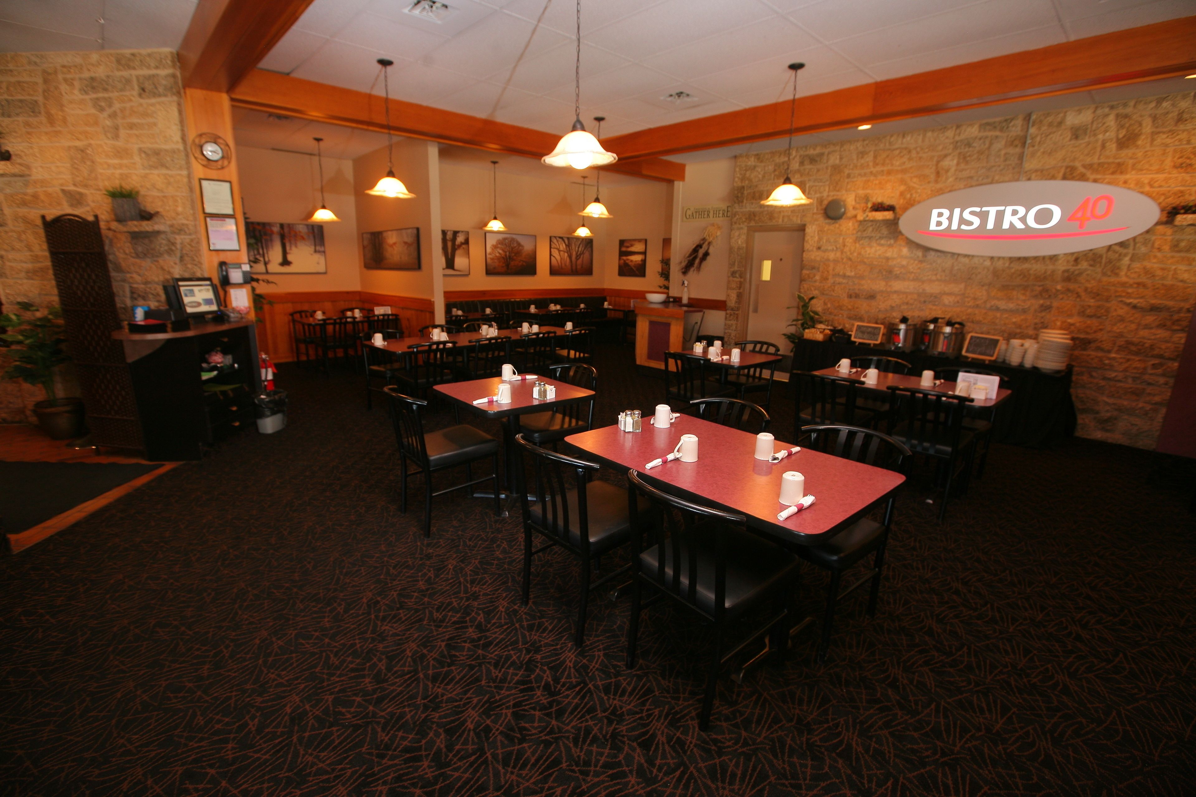 A restaurant interior with multiple tables and chairs, a stone wall, and a sign reading "BISTRO 40".