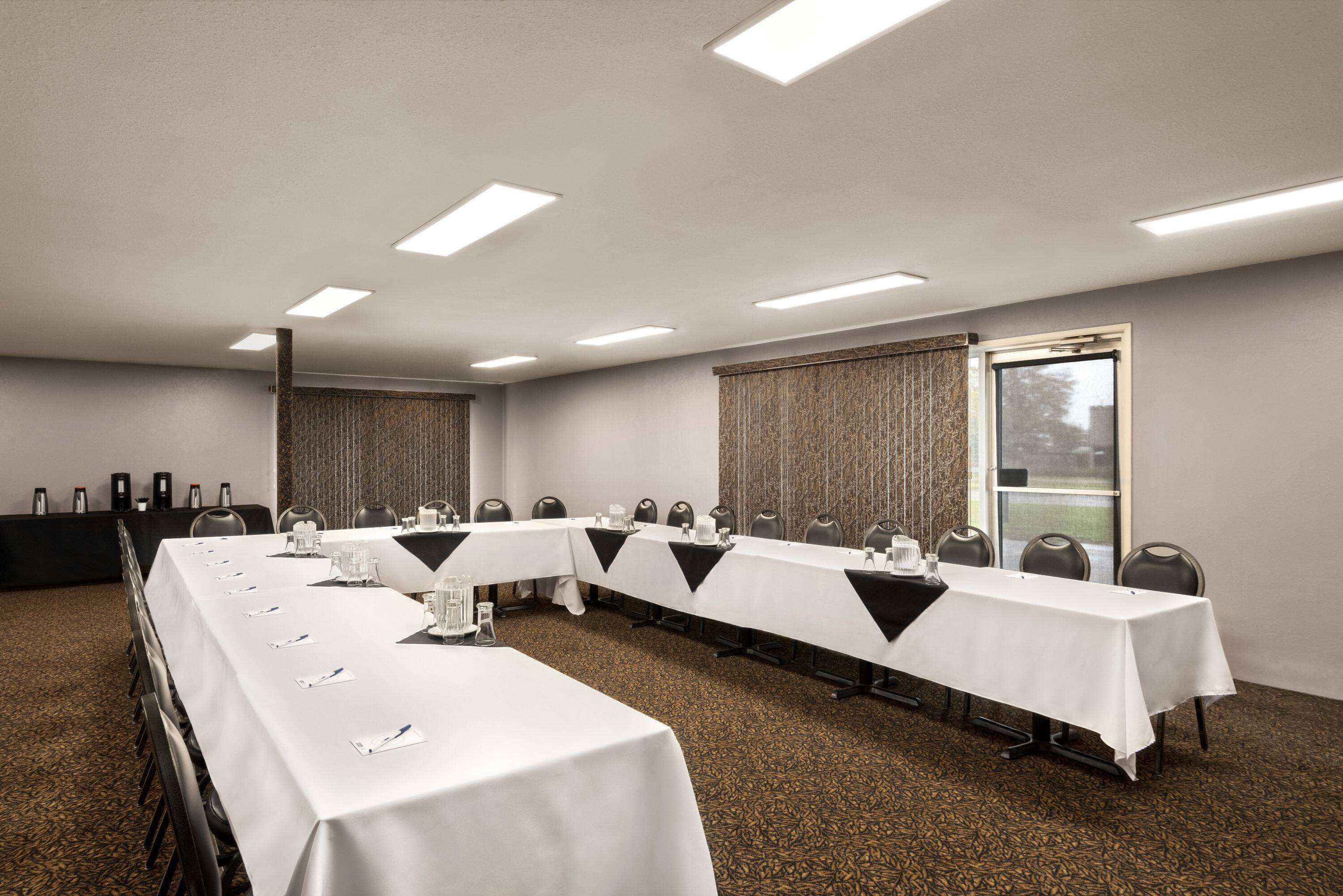 A conference room with a long table, chairs, and a projector screen.