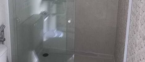 A glass-enclosed shower stall with a toilet and sink visible through the glass.