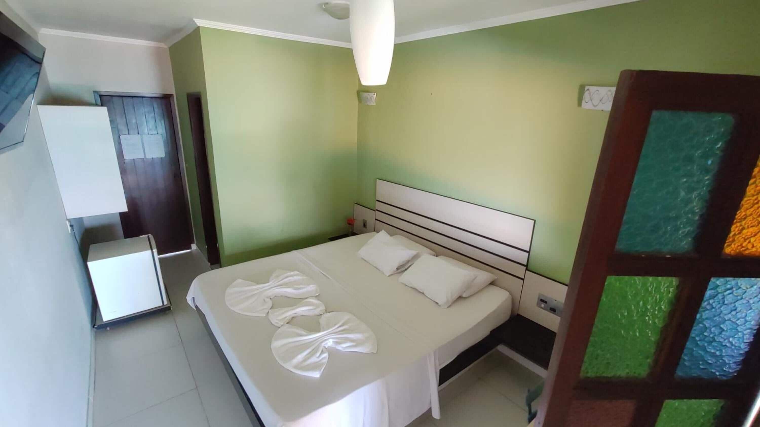 Una habitación de hotel con una cama, una mesita de noche, un escritorio y un armario.