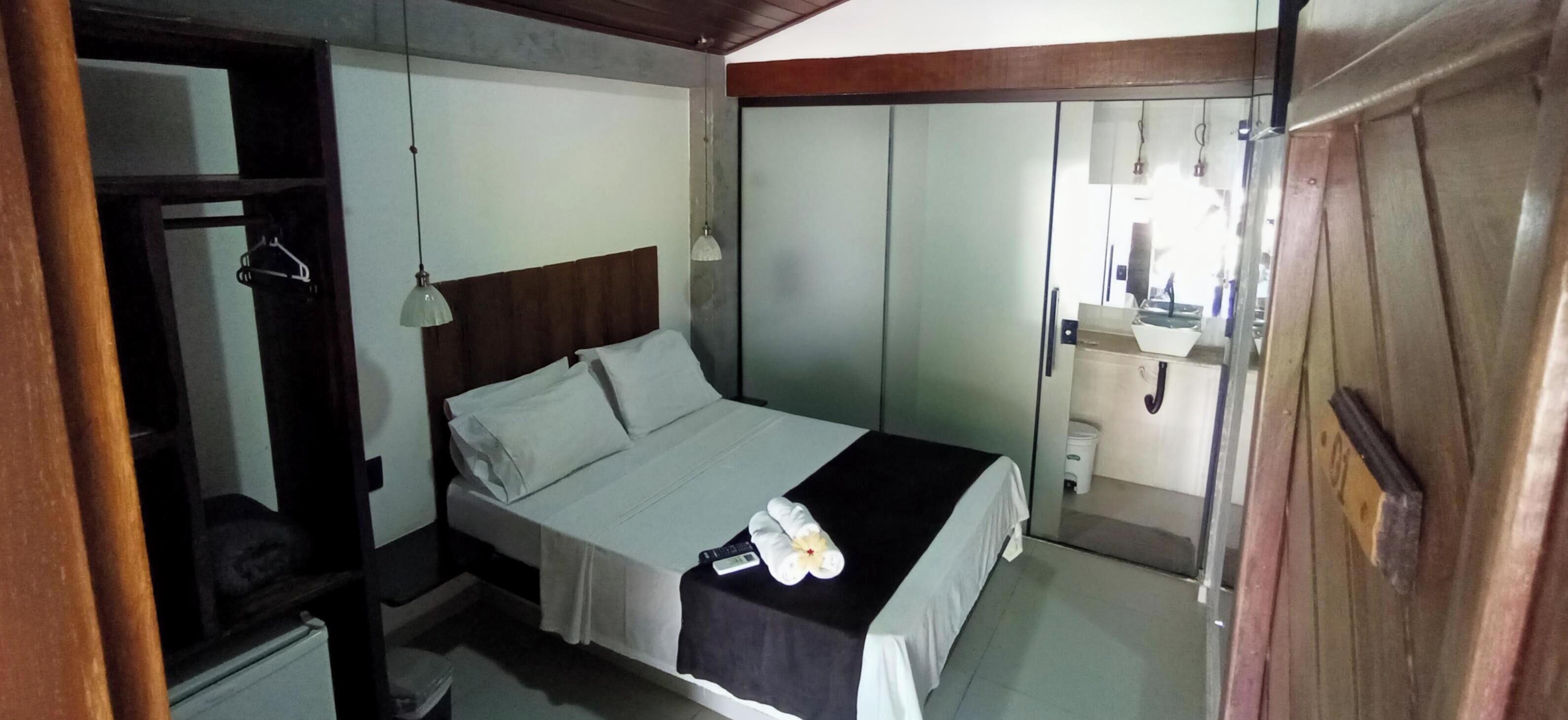A bedroom with a bed, a wardrobe, a mirror, and a bathroom visible through a sliding door.