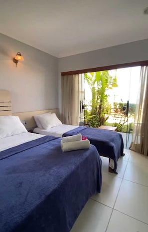 A hotel room with two beds, a large window with curtains, and a view of greenery outside. - Pousada Marajoara (Tibau do Sul)