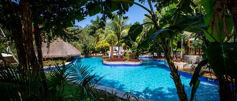 A tropical pool surrounded by lush greenery and palm trees.