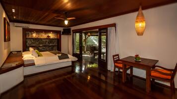 A room with a bed, a dining table with chairs, a ceiling fan, and a view of the outdoors.