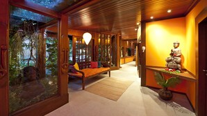 A modern interior with wooden flooring, a bench, a statue, and a glass wall with plants. - Sombra e Agua Fresca Floresta (Tibau do Sul)