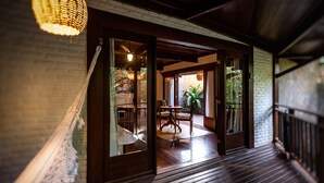 A wooden deck with a glass door leading to a dining area with a table and chairs. - Sombra e Agua Fresca Floresta (Tibau do Sul)