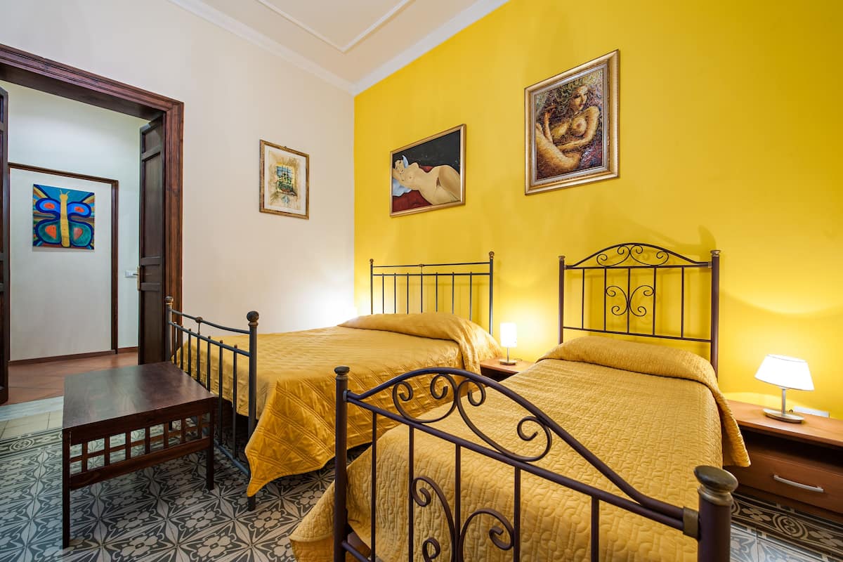 Habitació amb dos llits, una taula de fusta i un paviment amb disseny.