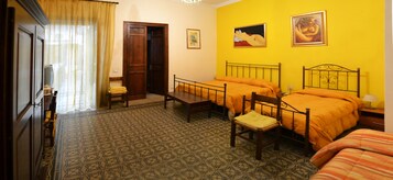 Una habitación con dos camas, una silla, una mesita y una puerta.