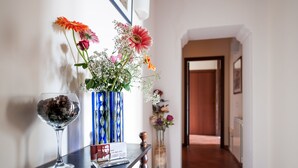 Un área de recepción con un florero de cristal, una fotografía enmarcada y un cartel sobre una mesa de madera oscura.