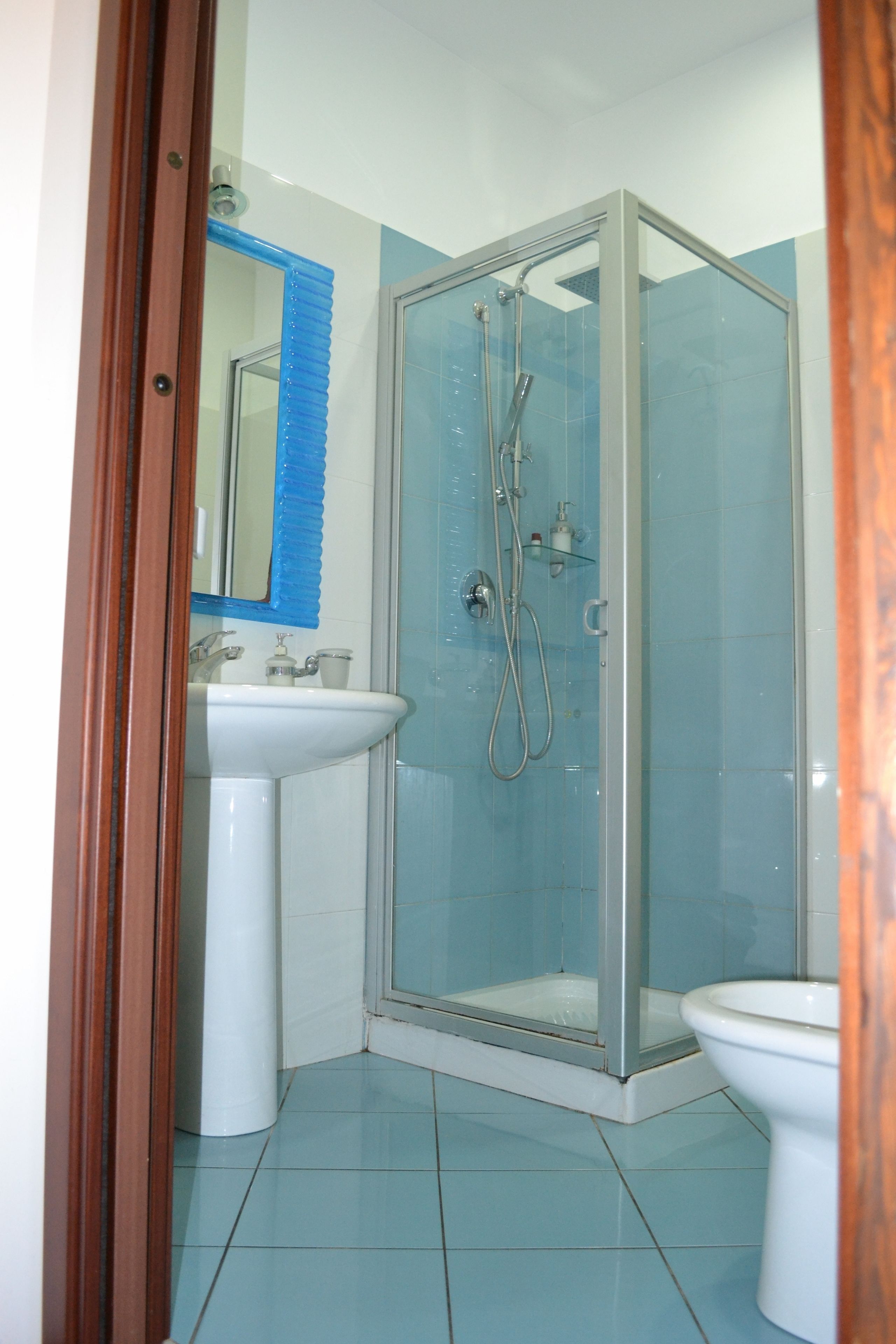 A bathroom with a glass-enclosed shower, a sink, and a toilet.