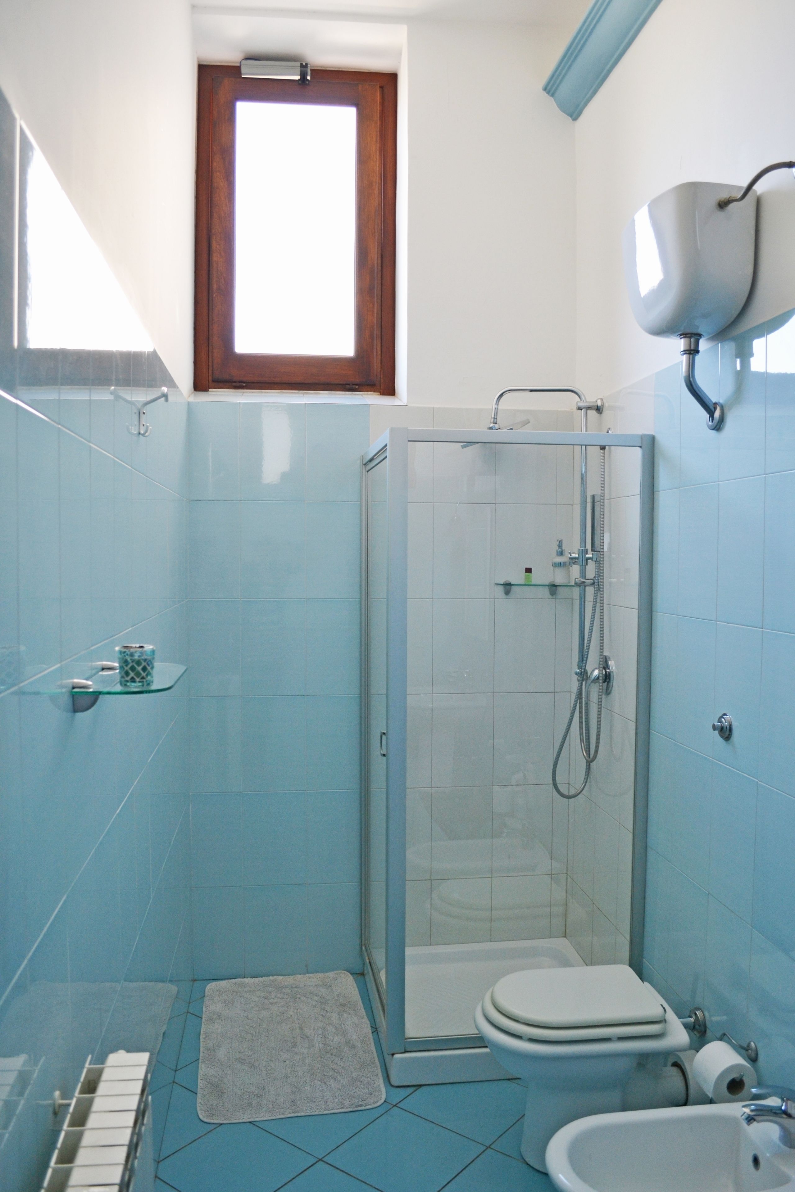 A bathroom with a glass-enclosed shower, a toilet, a bidet, and a sink.