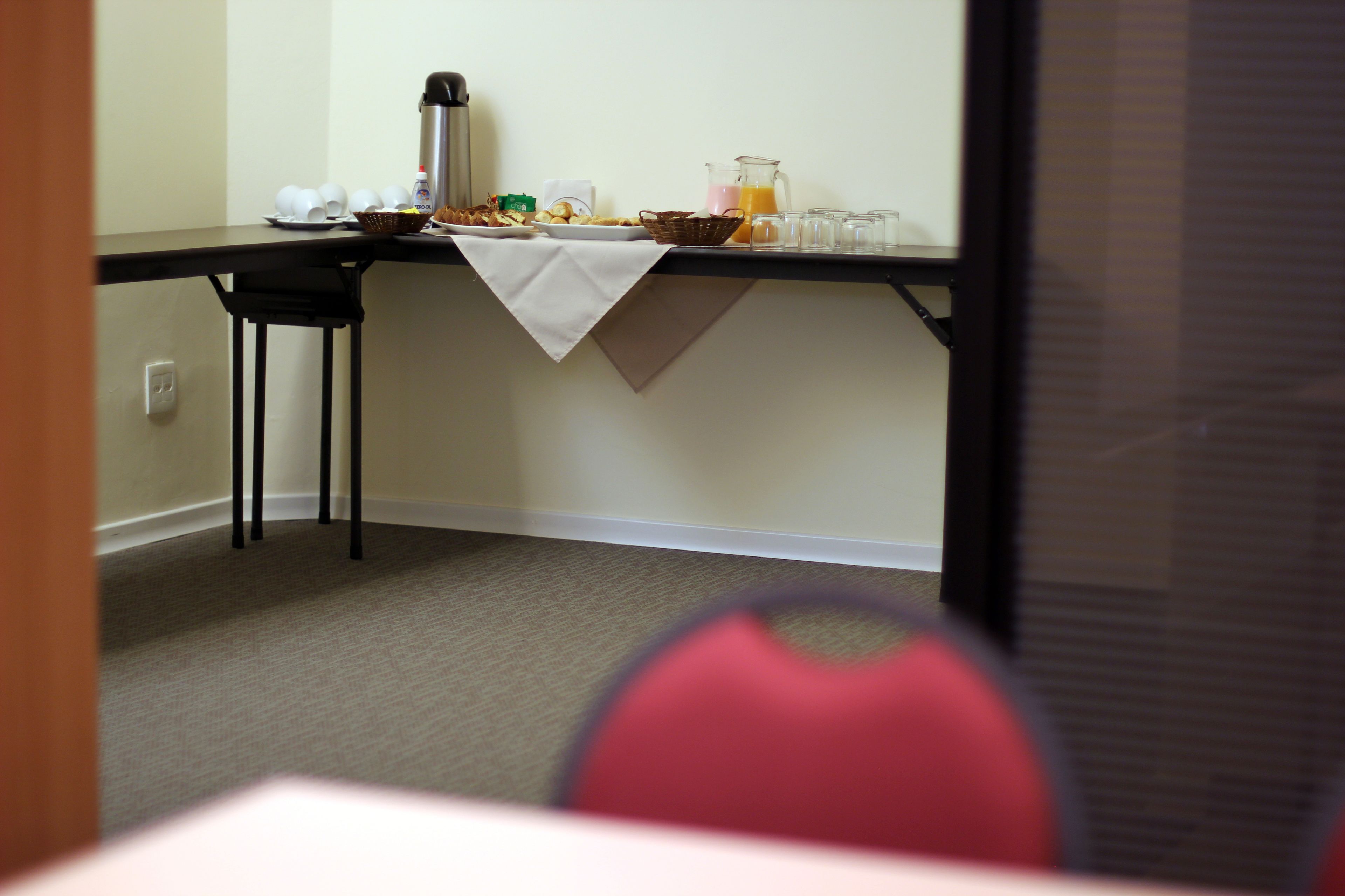 A breakfast table with a coffee pot, juice pitcher, and various breakfast items.