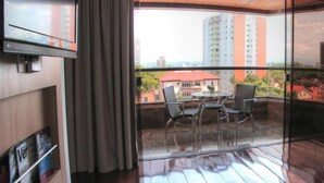 Een hotelkamer met balkon, een bed, een televisie en een tafel met stoelen.
