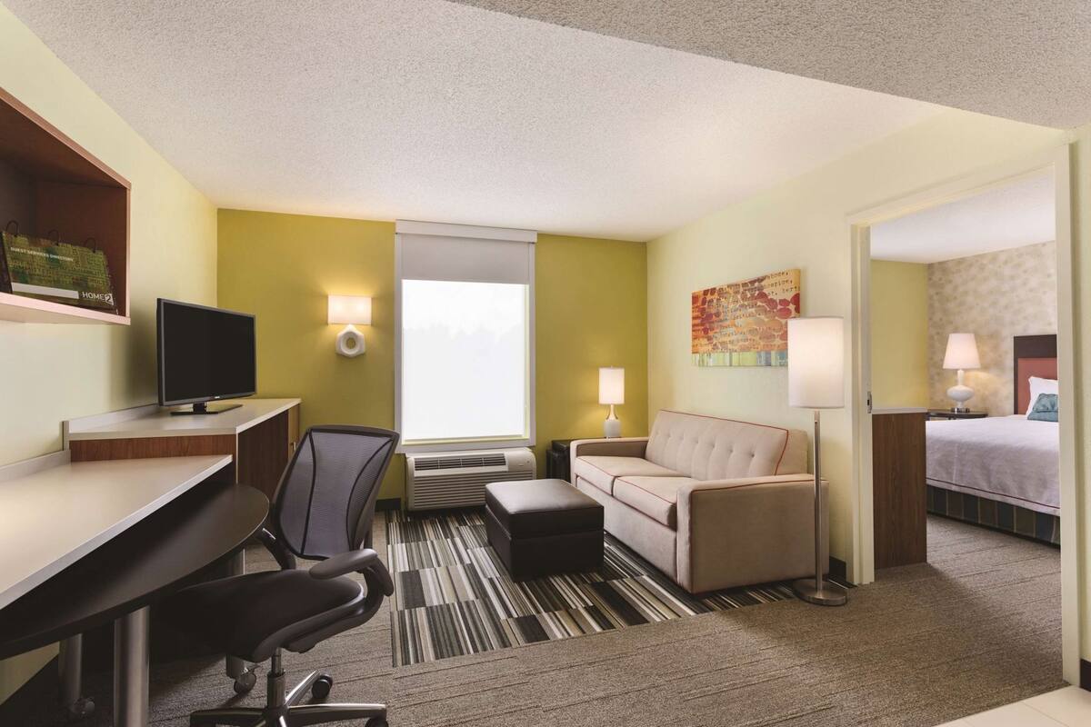 Een hotelkamer met een bureau, stoel, bank en bed.