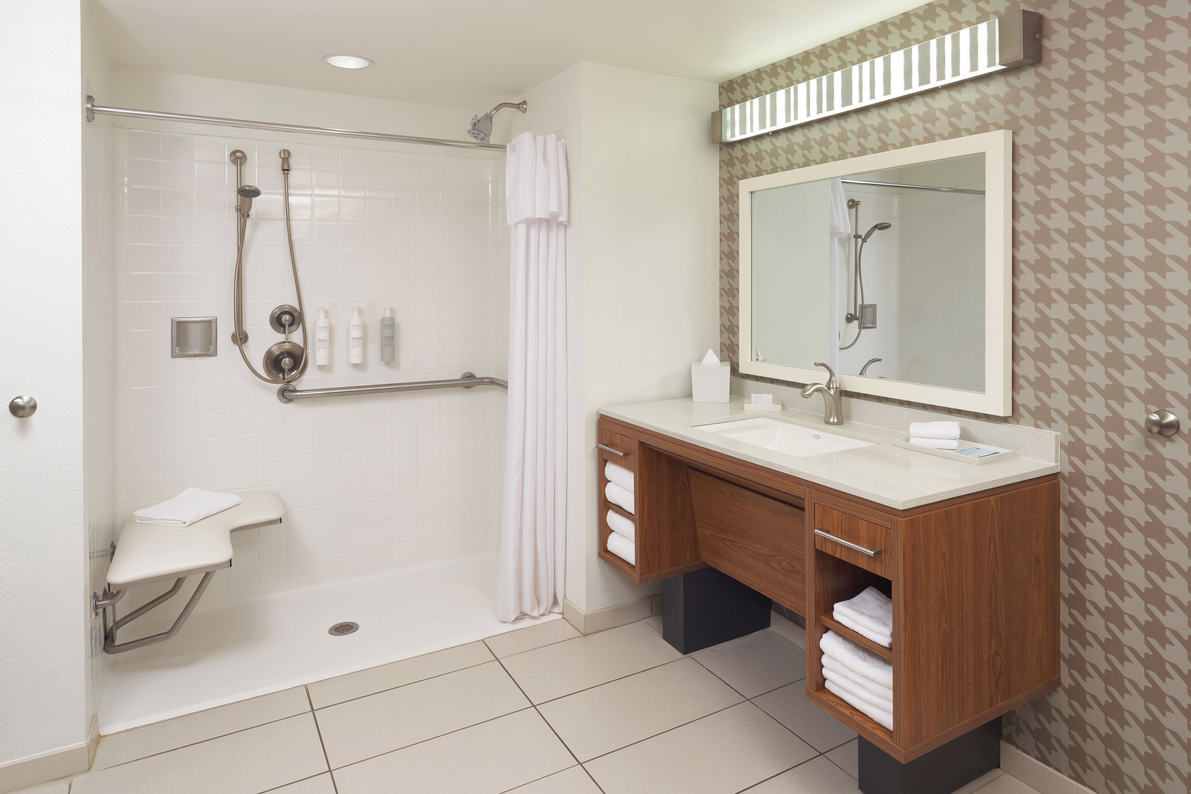 A modern bathroom with a walk-in shower, a vanity with a mirror, and a toilet with a grab bar.
