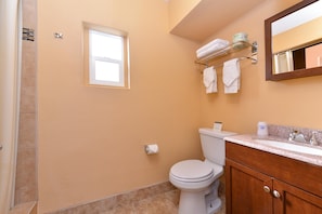 A bathroom with a toilet, sink, vanity, towel rack, and a window. - Americas Best Value Inn Porterville (Porterville)