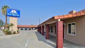 A hotel with a clear blue sky, a sign for 'Americas Best Value Inn by Vantage', and a red-tiled roof.