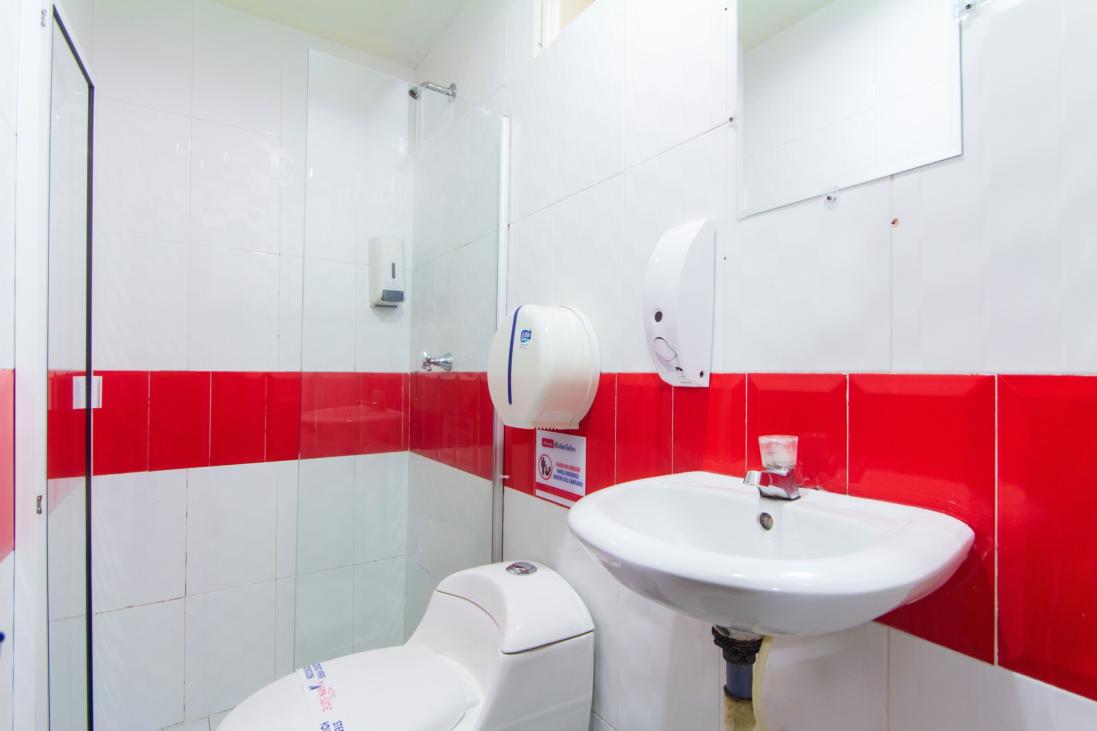 A bathroom with a toilet, sink, and hand dryer.
