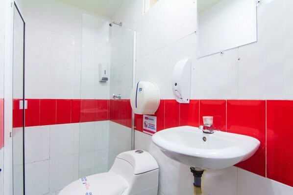 Une salle de bain équipée de toilettes, d’un lavabo et d’un sèche-mains.