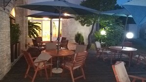 Une terrasse extérieure avec des tables et des chaises en bois, des parasols et des plantes en pot.