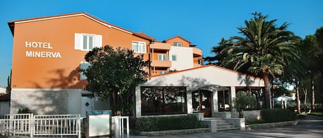 A hotel named "Hotel Minerva" with a modern architectural style, featuring a prominent entrance and a covered outdoor seating area.