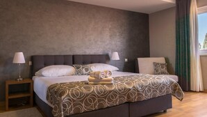 Une chambre d’hôtel moderne avec un grand lit, deux tables de chevet et une vue sur l’extérieur.
