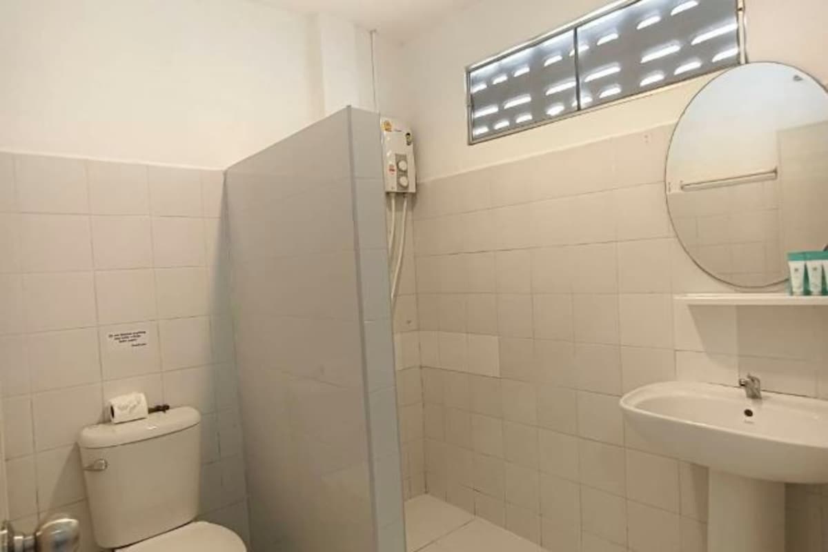 A bathroom with a toilet, a shower enclosure, a sink, and a mirror.