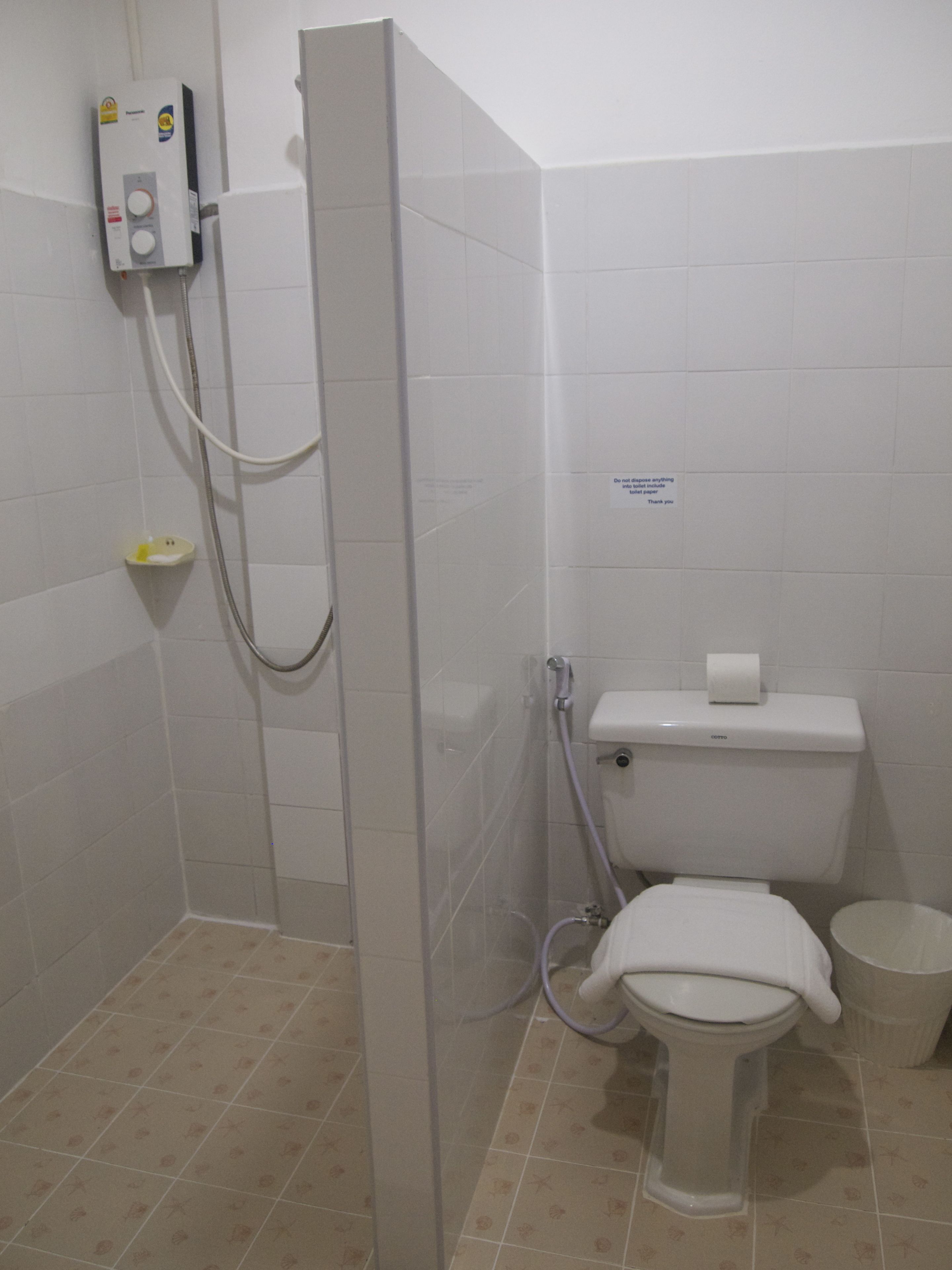 Casa de banho com cabine de duche, sanita e rolo de papel higiénico.