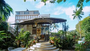 A restaurant with a covered outdoor seating area, steps leading up to the entrance, and lush tropical plants around. - KokosNuss Garden Resort (Coron)