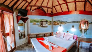 A room with a bed, a TV, a mural, and a view of water. - KokosNuss Garden Resort (Coron)