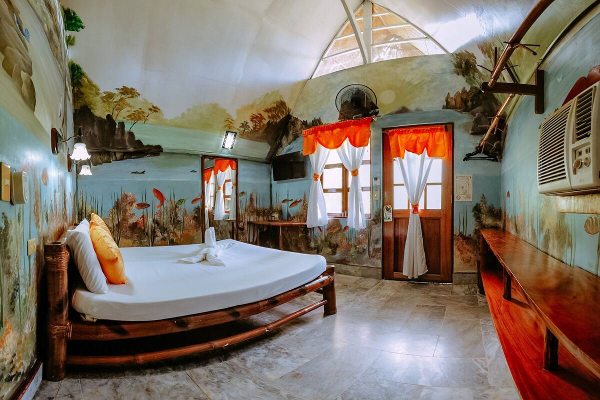 A room with a bed, a bench, and a mural on the wall.