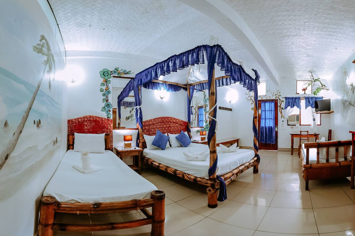 A room with two beds, a TV, and a desk.