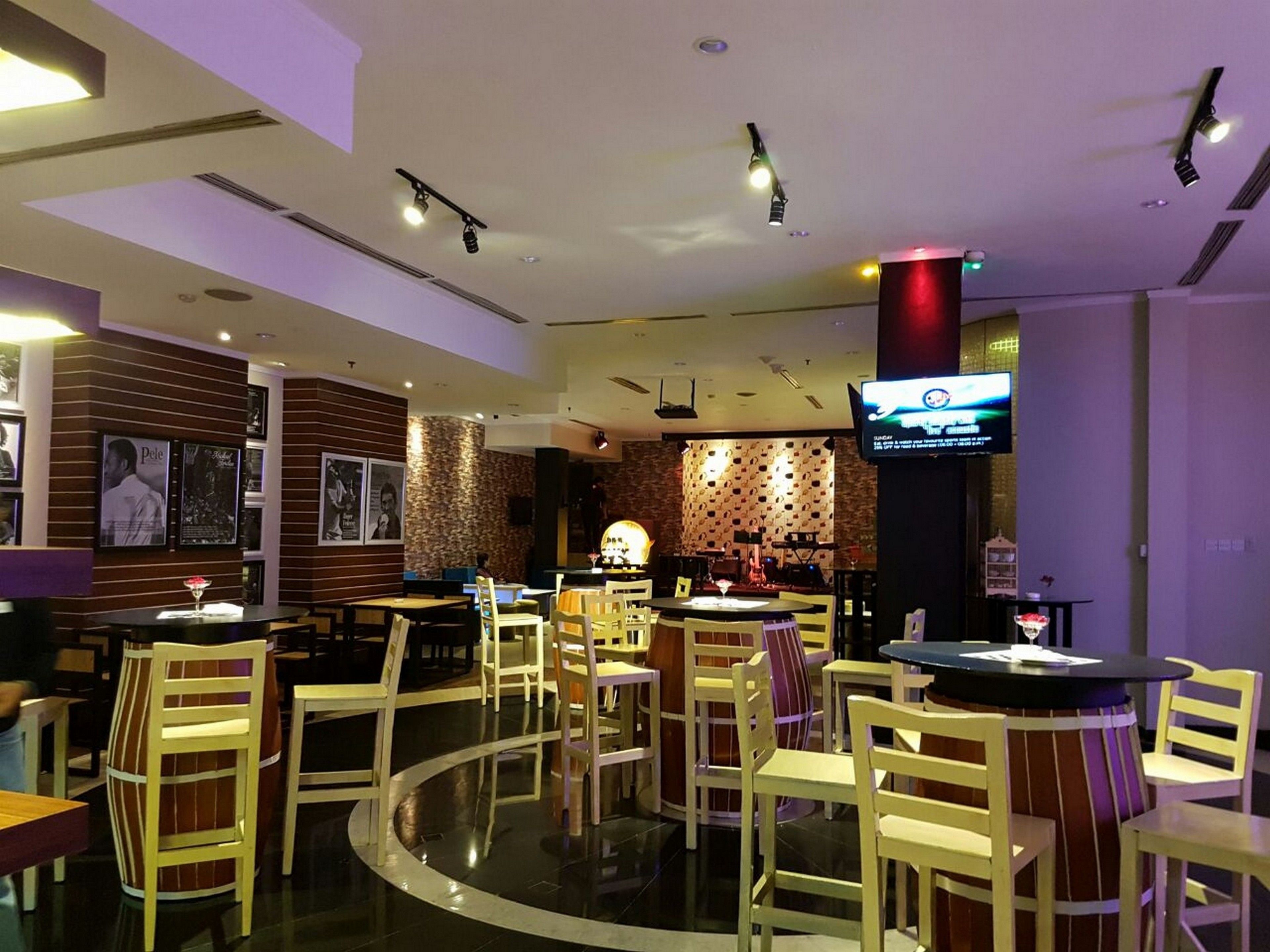 A restaurant with a bar area, multiple tables and chairs, and a television mounted on the wall.