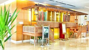 A lobby with a traditional wooden structure, a staircase, and a large potted plant.