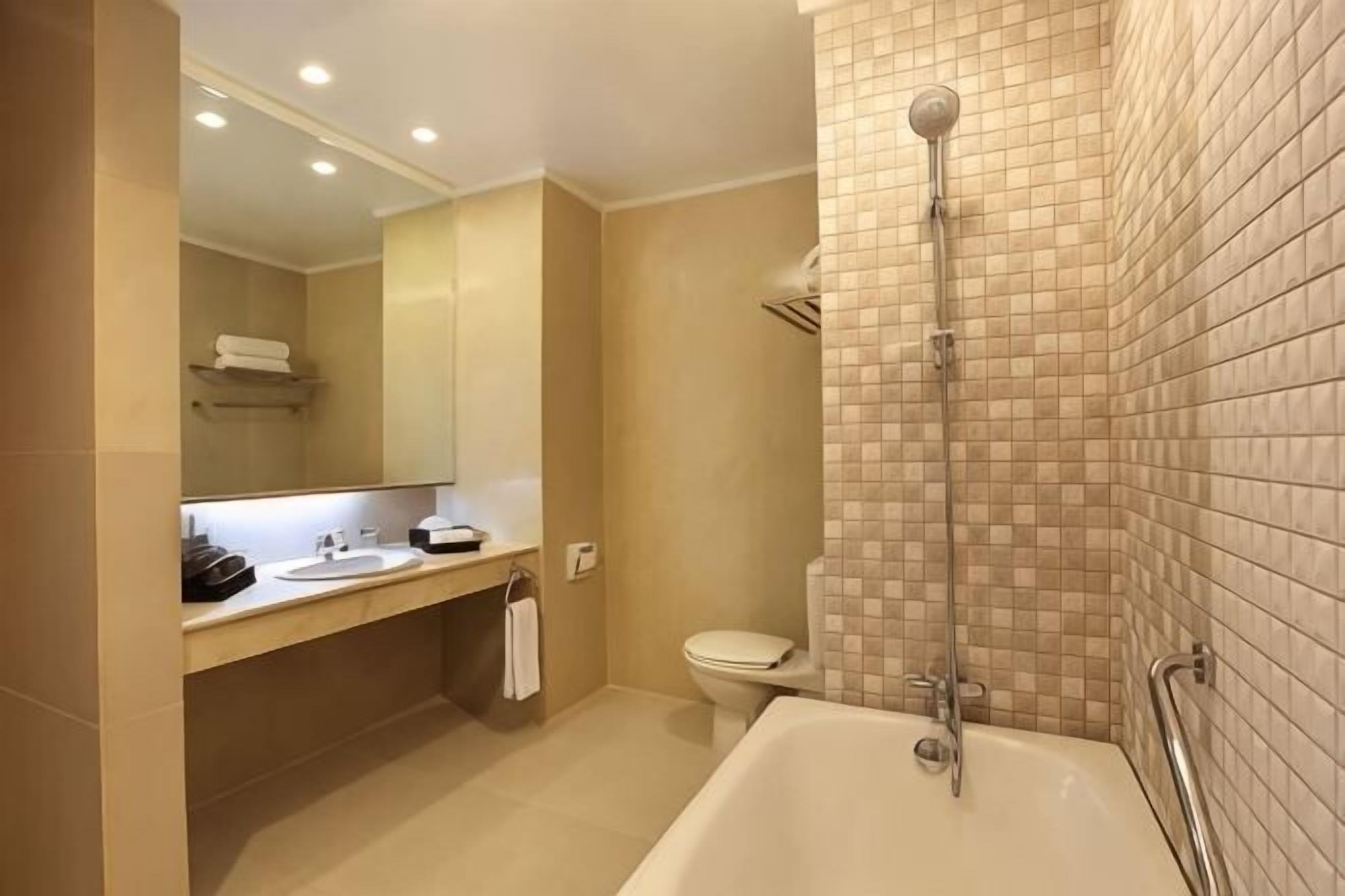 A bathroom with a bathtub, toilet, sink, and a shower area.