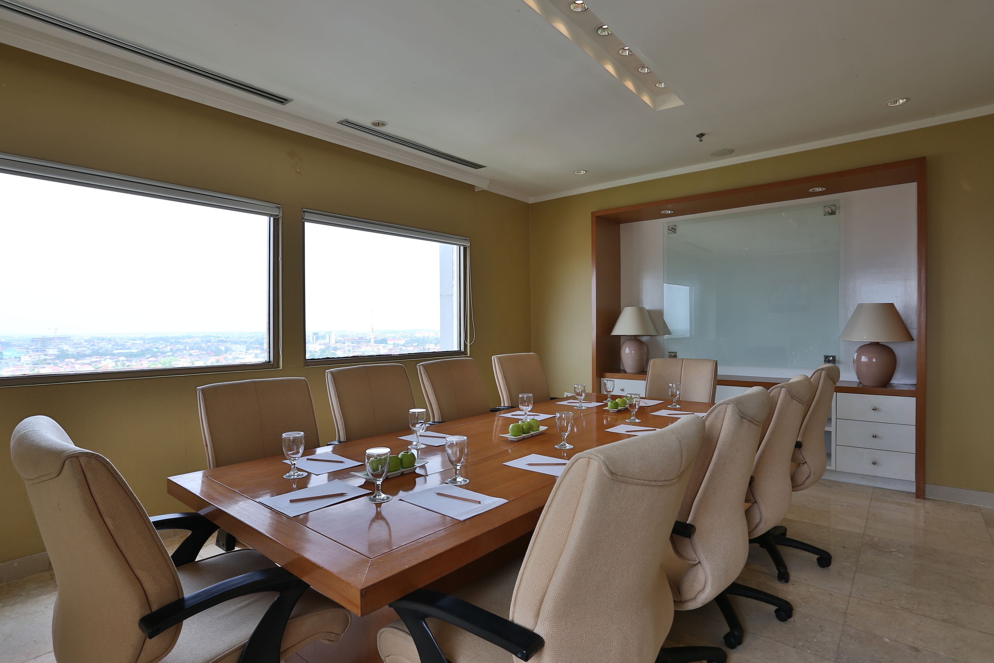 Uma sala de conferência com uma mesa comprida, várias cadeiras e grandes janelas com vista para a cidade.
