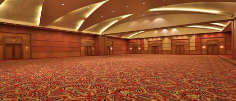 A spacious hall with a patterned carpet and a high ceiling with recessed lighting.