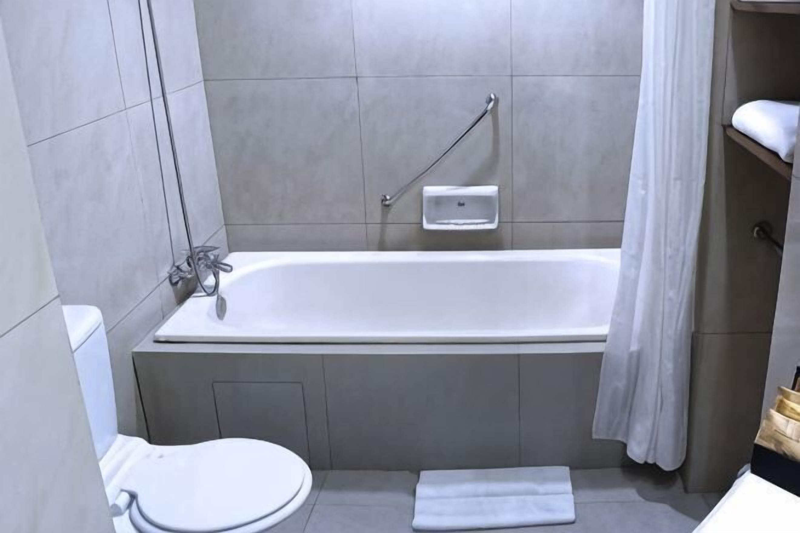 A bathroom with a bathtub, toilet, and a towel rack.