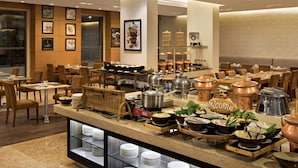 A buffet setup with various food items and utensils, a 'Welcome' sign, and a seating area with tables and chairs.