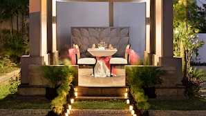 An outdoor dining area with a modern design, featuring a table and chairs under a pergola.