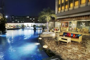 A swimming pool with a sunken seating area and a palm tree. - Aryaduta Palembang (Palembang)