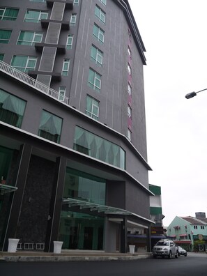 Ein modernes Hotel mit einem markanten Eingang, großen Fenstern und einem sichtbaren Balkon.