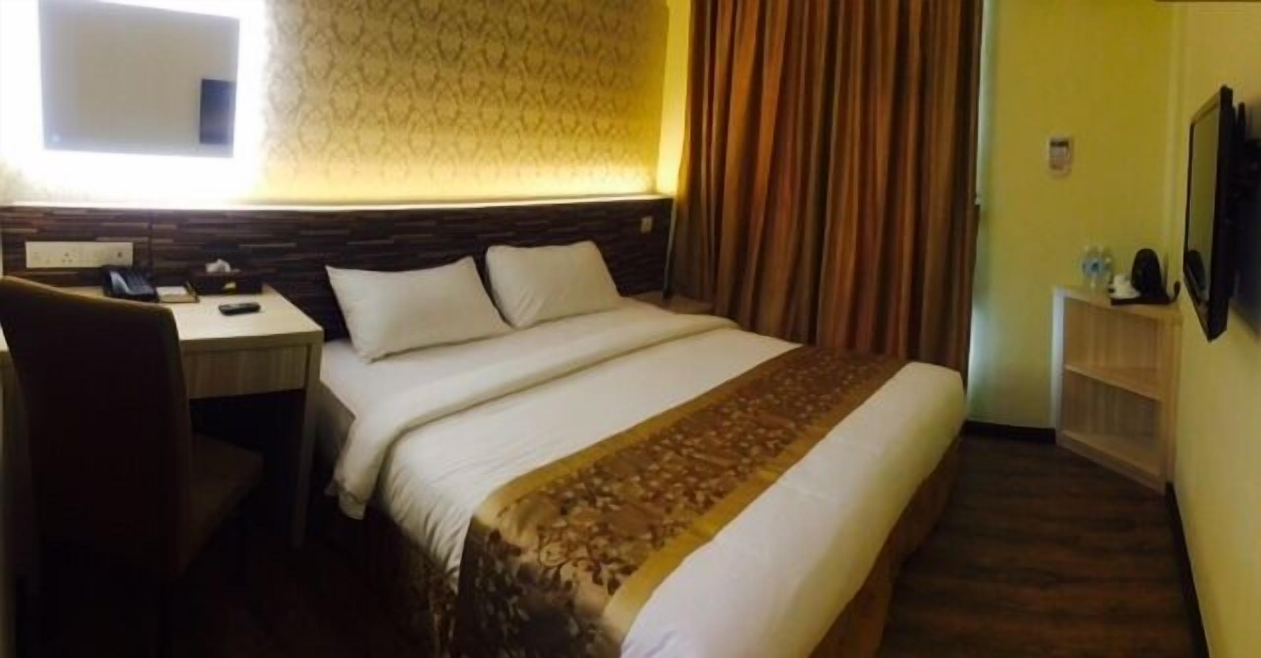 Una habitación de hotel con una cama, un escritorio, una silla, un televisor y una ventana con cortinas.