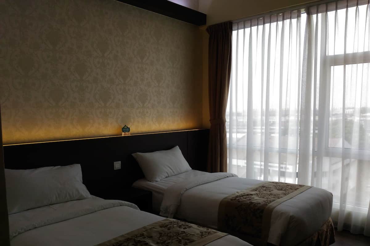 Habitación de hotel con dos camas, cabecera con tira de luz, vista de la ciudad a través de cortinas translúcidas y un corredor de cama estampado.