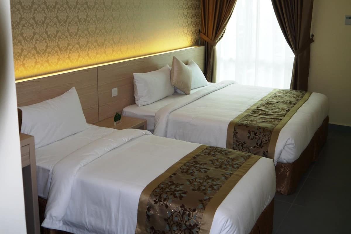 Una habitación de hotel con dos camas, un papel tapiz estampado, una ventana con cortinas y una mesita de noche.