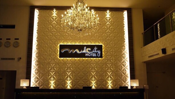 A hotel reception area with a modern chandelier, a geometric patterned wall, and a sign that reads "Midcity Hotel". - Midcity Hotel Melaka (Malacca City)