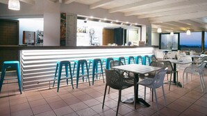 A spacious indoor dining area with a long counter and multiple seating options, including bar stools and tables. - Ida Village I & II (Hersonissos)