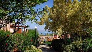 A garden pathway leading to a building with a view of the sea. - Ida Village I & II (Hersonissos)