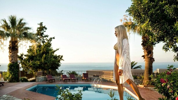 A woman walking by a pool with a view of the sea. - Ida Village I & II (Hersonissos)